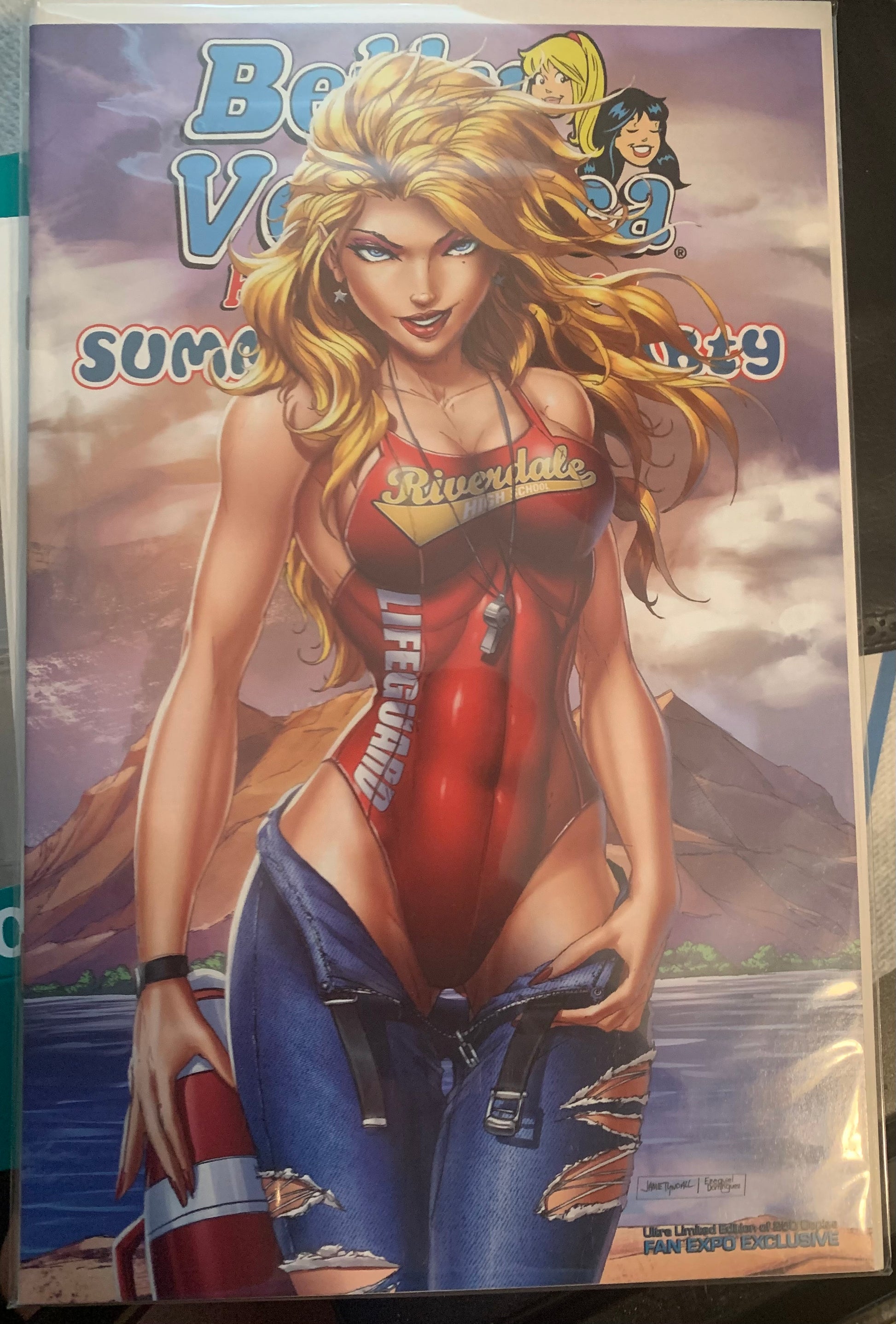 Comic book cover with Betty in a red lifeguard swimsuit and ripped jeans against a mountainous beach background
