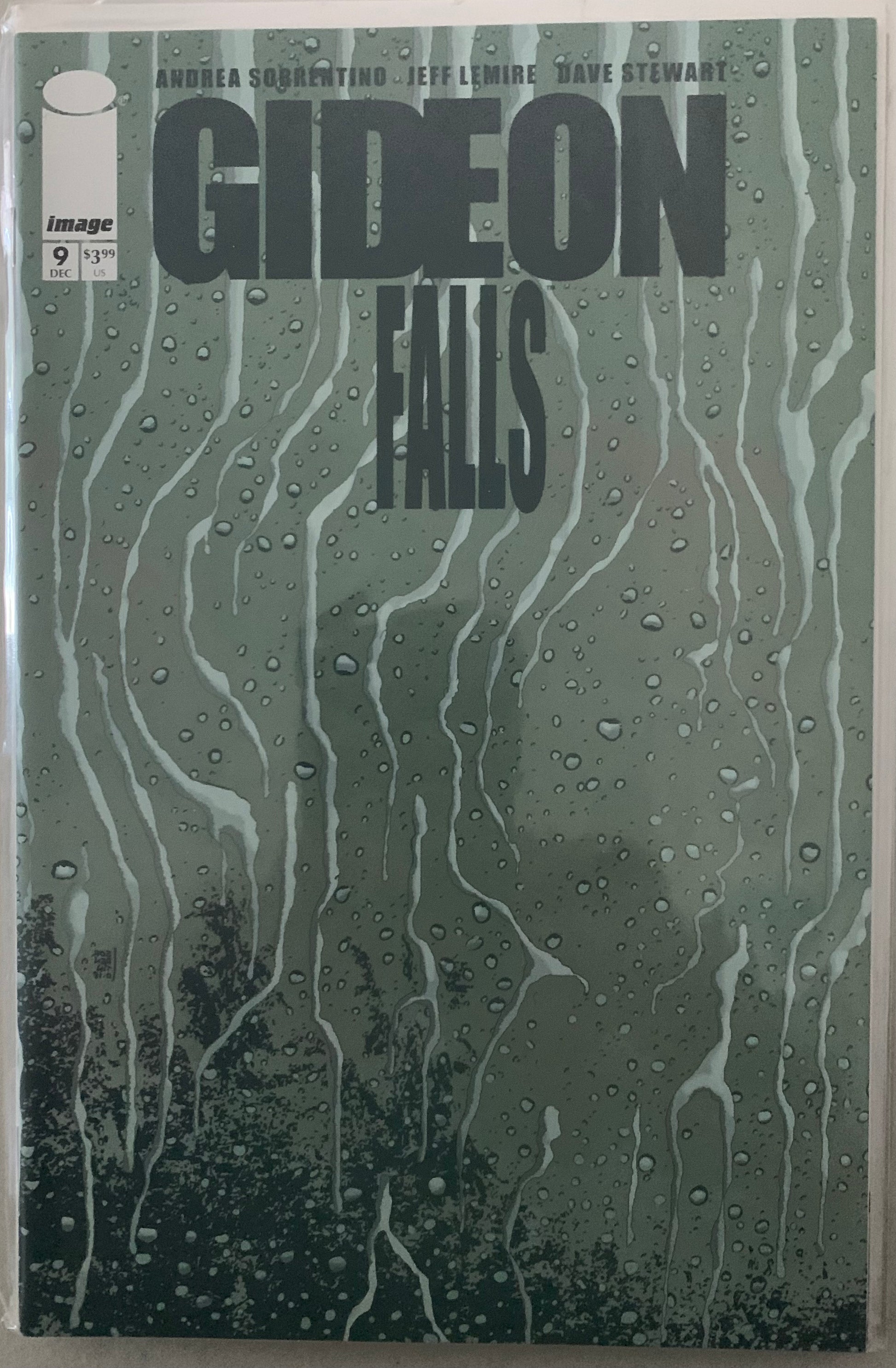Comic book cover of 'Gideon Falls' with beaded water droplets on a glass surface.