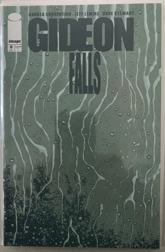 Comic book cover of 'Gideon Falls' with beaded water droplets on a glass surface.