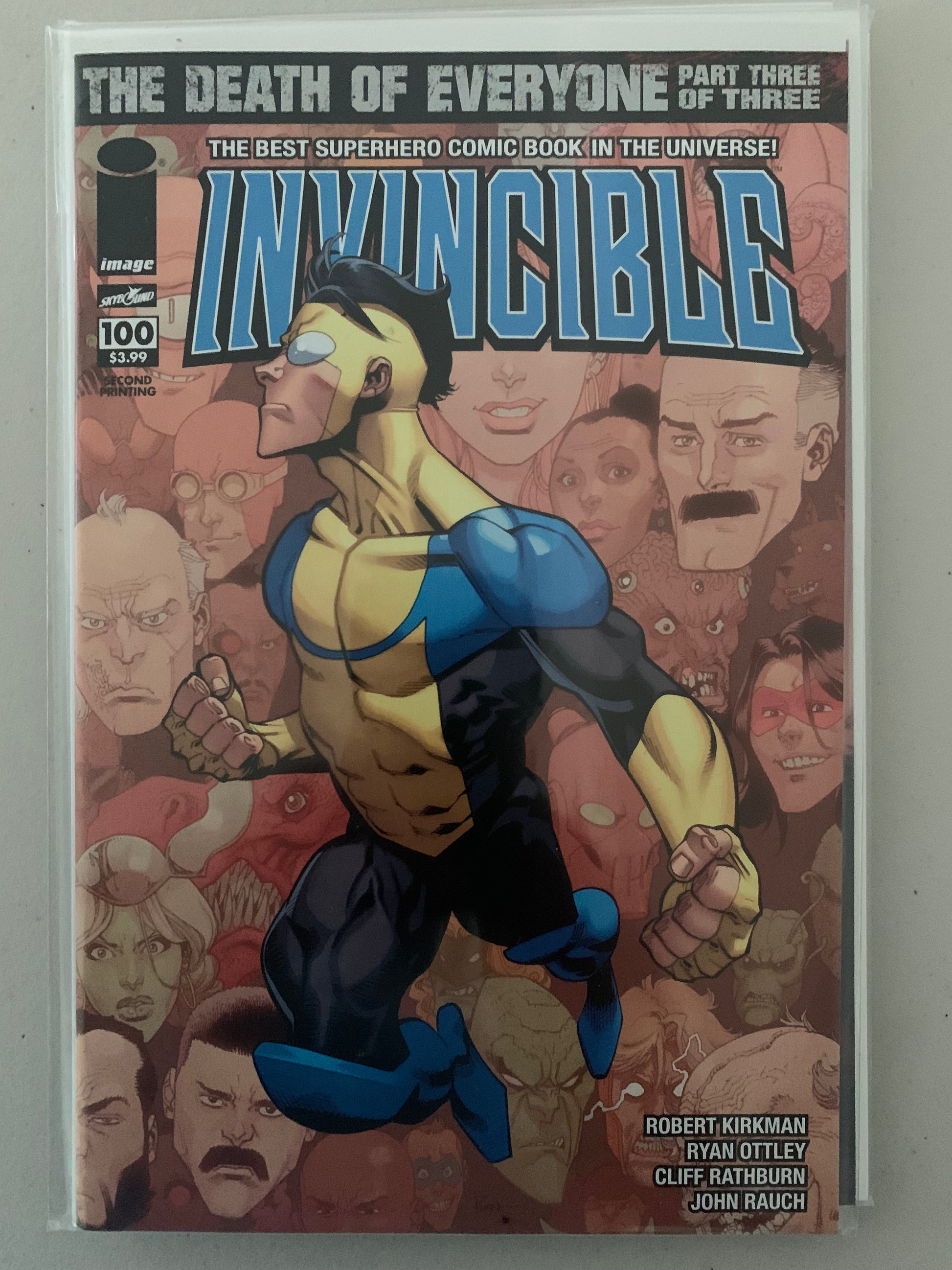 Comic book cover of 'Invincible' and text with other characters' faces in the background.