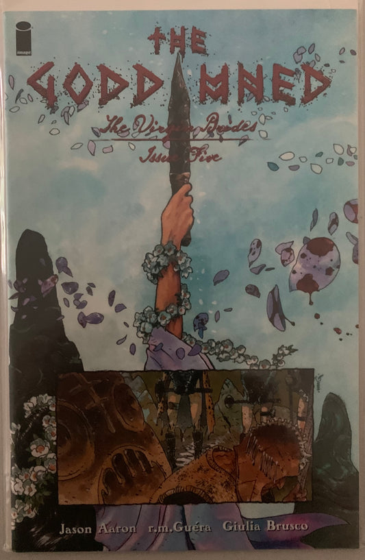 Comic book cover titled 
'The Goddamned' with a hand holding a sword and floral wreath against a blue sky background.